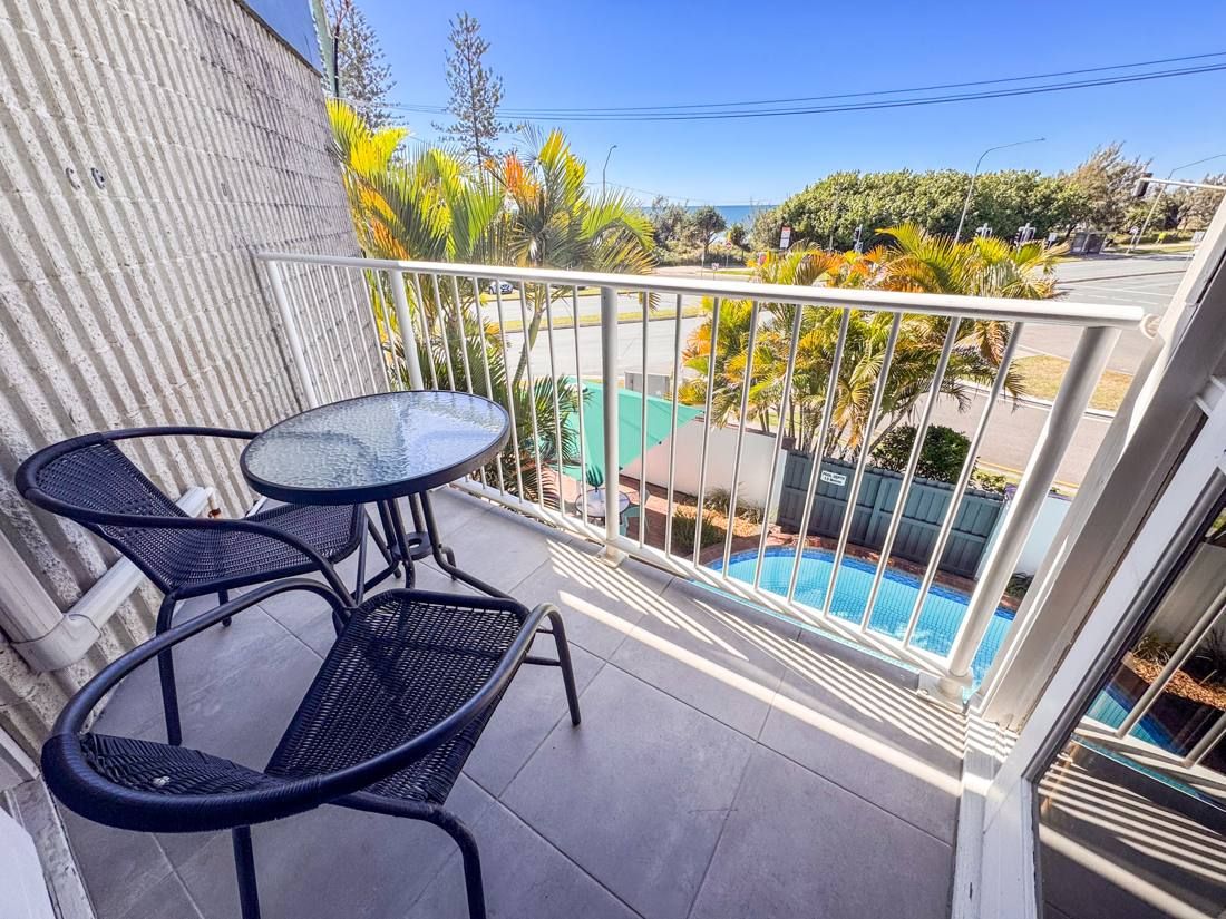 Balcony table and chairs with pool and garden views